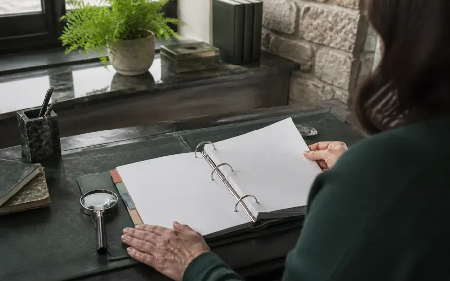 An open ring binder with tabbed dividers beside a magnifying glass