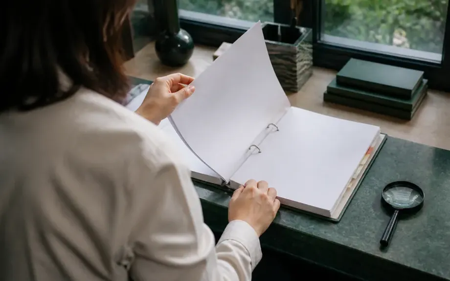 An open ring binder with tabbed dividers beside a magnifying glass